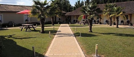 Un chemin menant à un bâtiment doté d’une terrasse et bordé de palmiers.