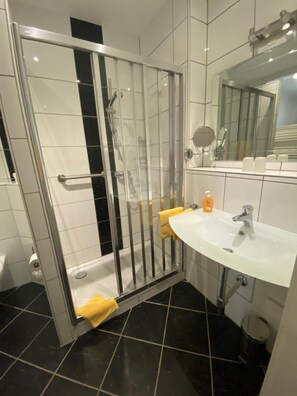 Un baño con ducha de vidrio, un lavamanos blanco y un espejo.