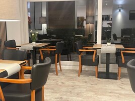 Un comedor moderno con mesas y sillas, un ventanal y vista al interior.