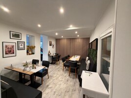 Uma área de jantar moderna com mesa de madeira, cadeiras pretas e parede listrada ao fundo.