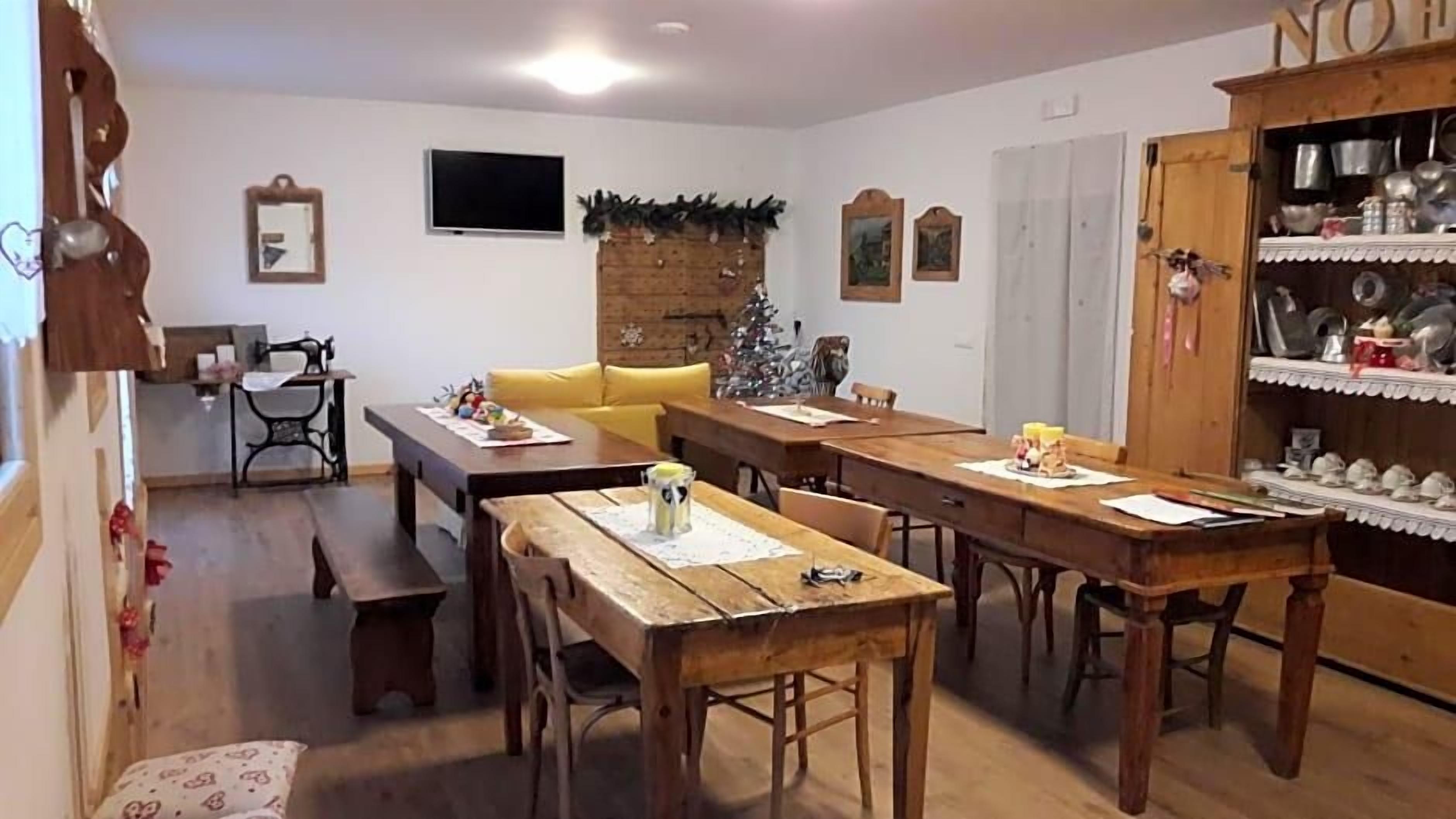 Un'area pranzo con tavoli e panche di legno, un piccolo albero di Natale e un armadietto con stoviglie.