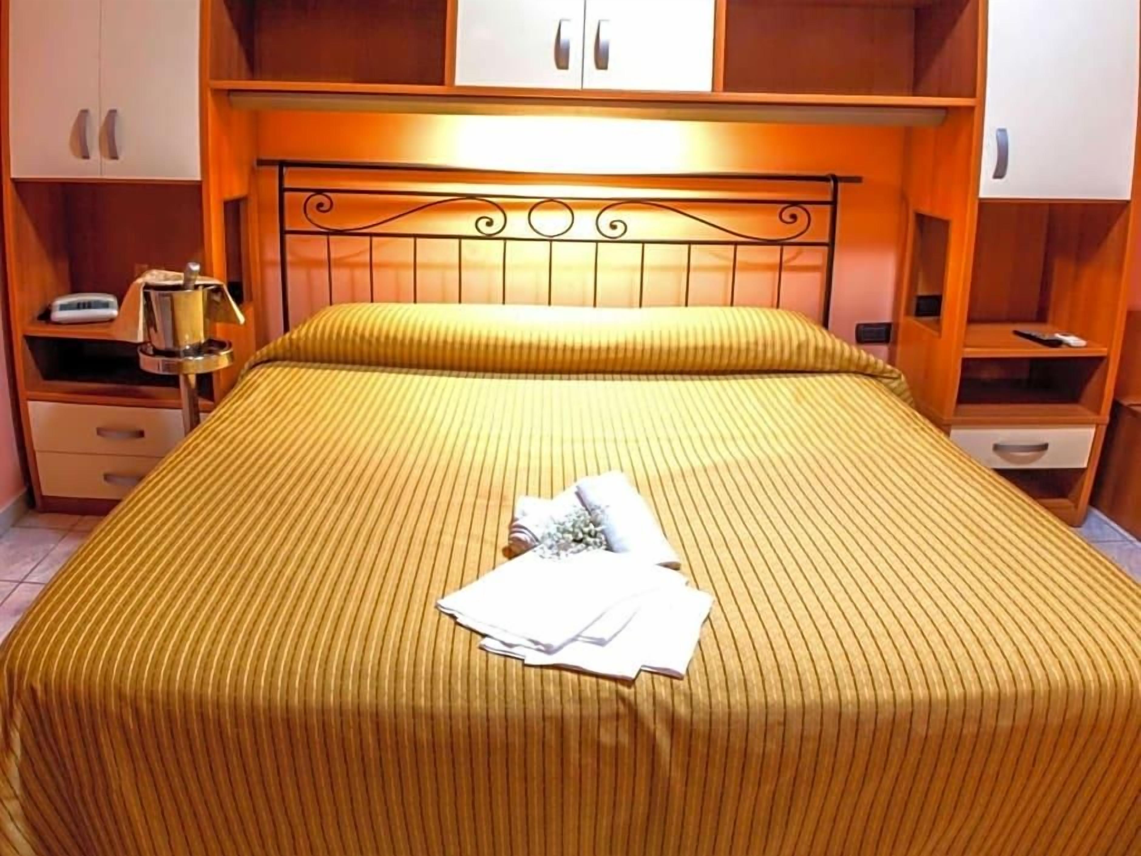 Une chambre d’hôtel comprenant un lit, une table de chevet, une commode et un placard.