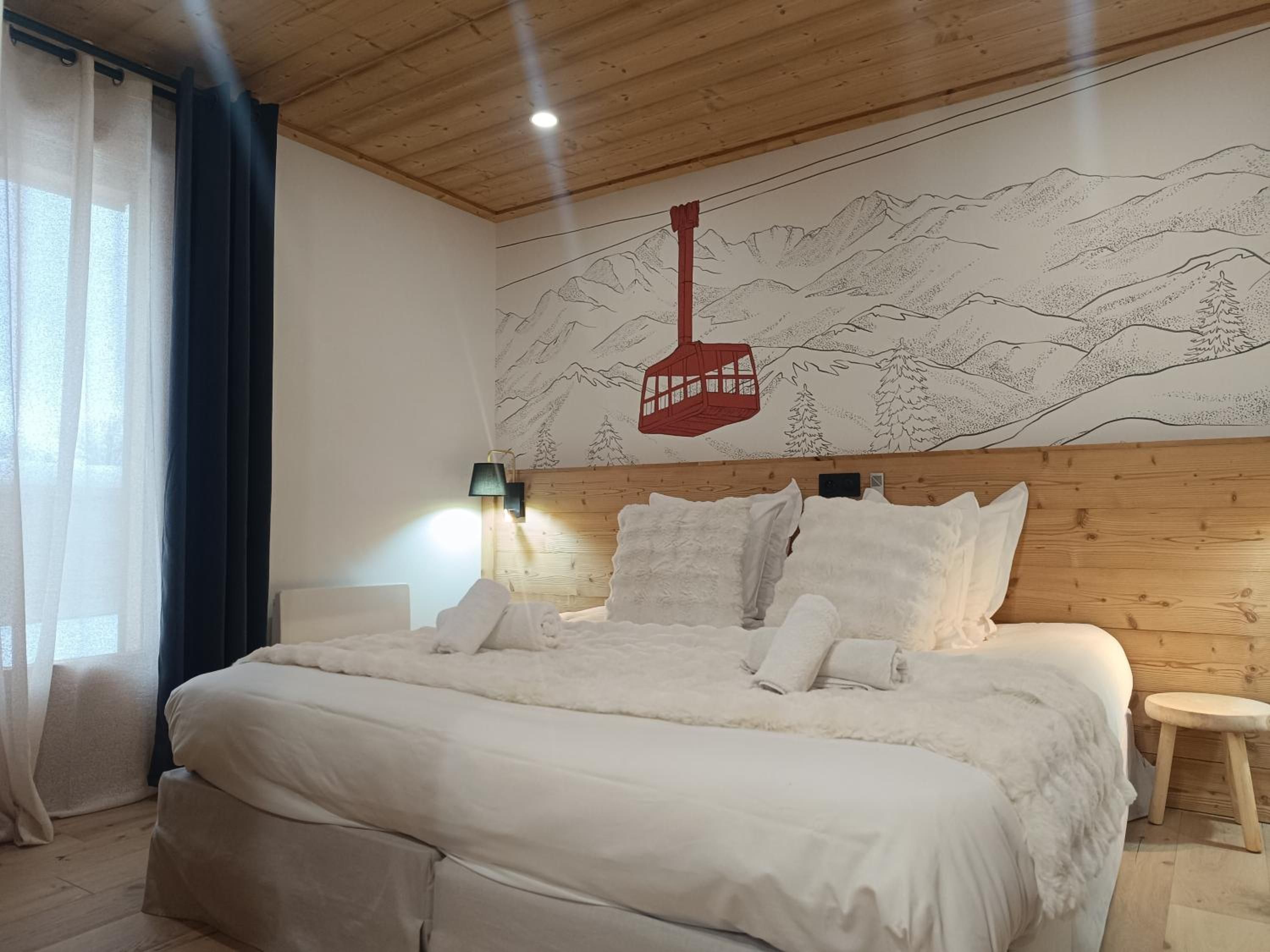 Un dormitorio con una cama grande, un cabecero con panel de madera, un mural de montañas, un farolillo rojo y un taburete pequeño.