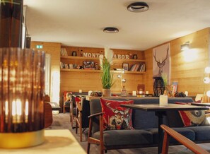 Un interior acogedor con paredes de madera, una zona de bar y diferentes disposiciones de asientos.
