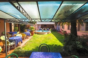 A covered outdoor patio with tables and chairs, a small pool, and a lawn area. - Hotel Sonia (Forte dei Marmi)