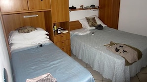 A bedroom with two beds, wooden wardrobes, a bedside table with a lamp, and a framed picture on the wall. - Hotel Adriana (Laigueglia)