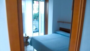 A bedroom with a bed, a window, and a door leading to a balcony. - Hotel Adriana (Laigueglia)
