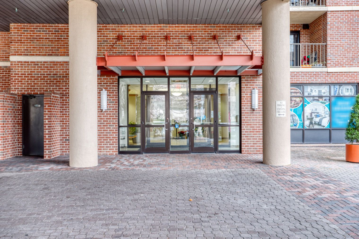 A brick building with a glass entrance, a fire escape, and a mural on the wall.