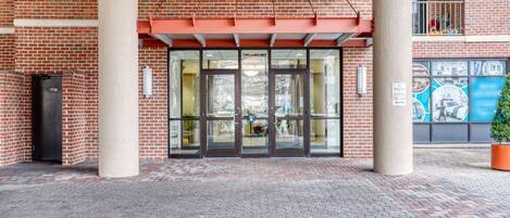 A brick building with a glass entrance, a fire escape, and a mural on the wall.