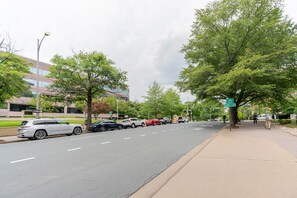 A street with parked cars, a sidewalk, and a building in the background. - Blueground | Clarendon, gym, nr Arlington Cemetery (Arlington)