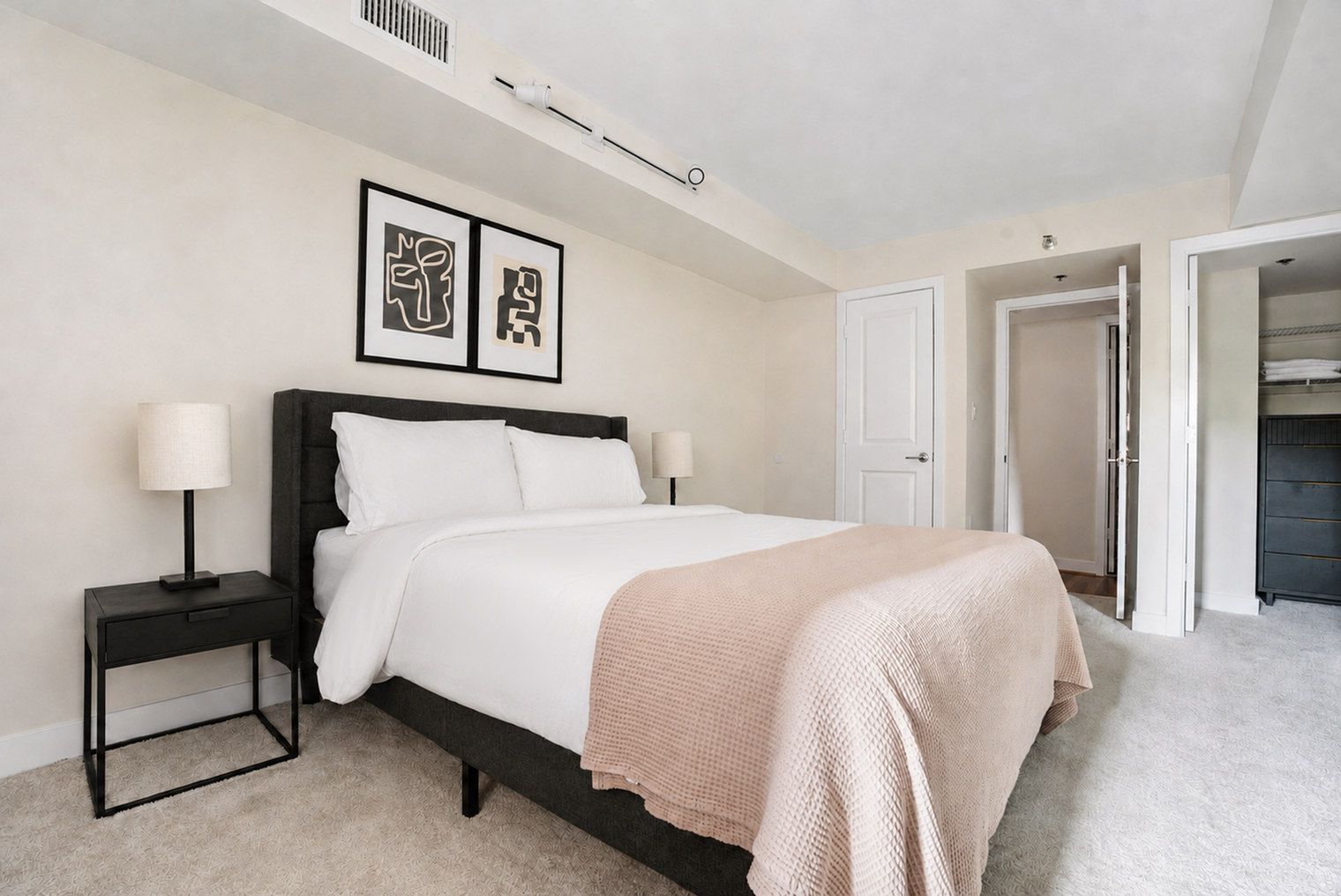 A bedroom with a bed, bedside tables, a closet, and a door.