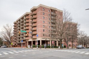 A multi-story brick building with balconies, a parking garage entrance, and a pedestrian crossing. - Blueground | Clarendon, gym, nr Arlington Cemetery (Arlington)