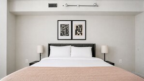 Une chambre d’hôtel avec un grand lit, deux lampes de chevet et deux œuvres d’art encadrées accrochées au mur.