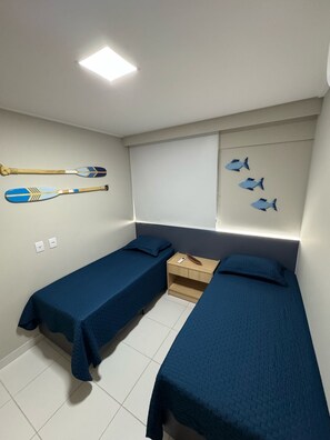 A bedroom with two single beds, a nightstand, a wall-mounted shelf with two paddles, and a wall decoration of fish. - 2-bedroom apartment in the Malia Beach Resort in Muro Alto, Porto de Galinhas (Ipojuca)