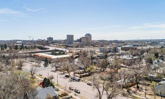A cityscape with a mix of modern and older buildings, a bridge, and a clear sky.