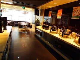 Interior de restaurante com balcão, cadeiras e uma planta.