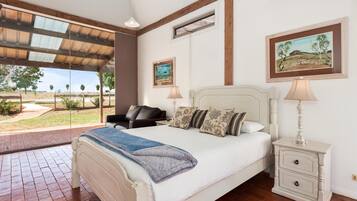A bedroom with a bed, bedside tables, a chair, and artwork on the walls.