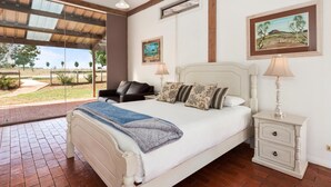 A bedroom with a bed, bedside tables, a chair, and artwork on the walls.