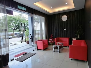 A hotel lobby with a reception desk, red seating area, and a large window with a view of the outside. - Nah Hotel (Johor Bahru)