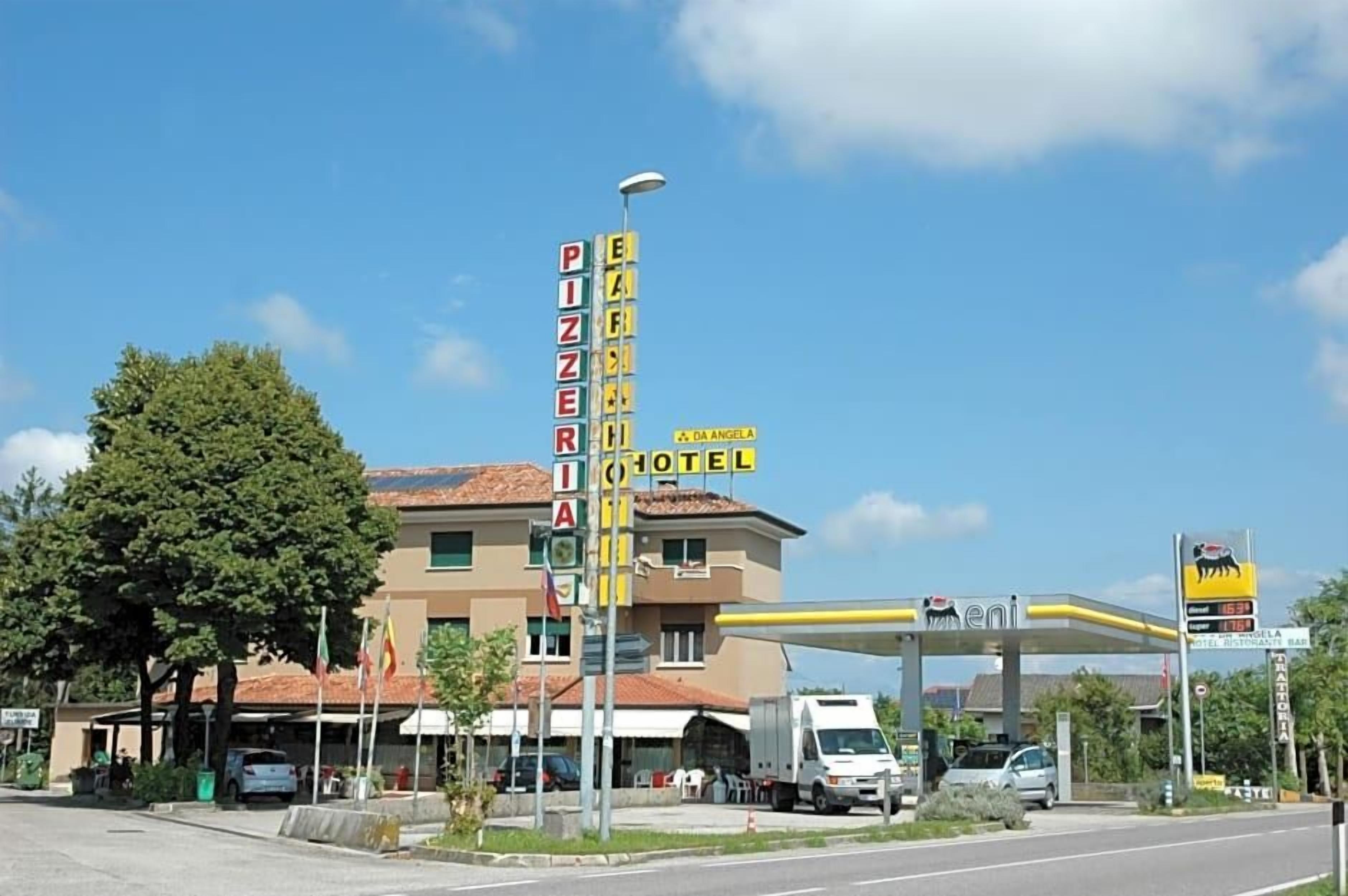 A hotel with a sign for a pizzeria and a gas station.