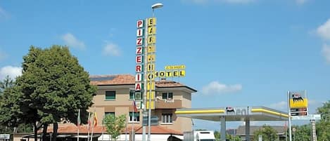 A hotel with a sign for a pizzeria and a gas station.