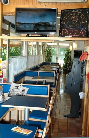En restaurang med avskilda sittplatser, en tv och en skylt med en pizza på.