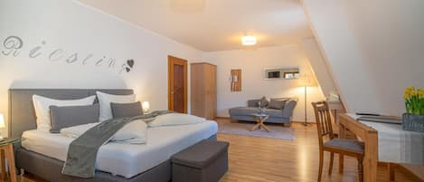 A modern bedroom with a large bed, a desk, and a dining area.