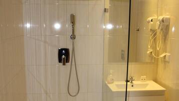 A modern bathroom with a glass shower enclosure, a white sink, and a mirror.