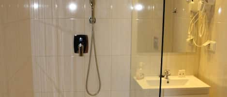 A modern bathroom with a glass shower enclosure, a white sink, and a mirror.