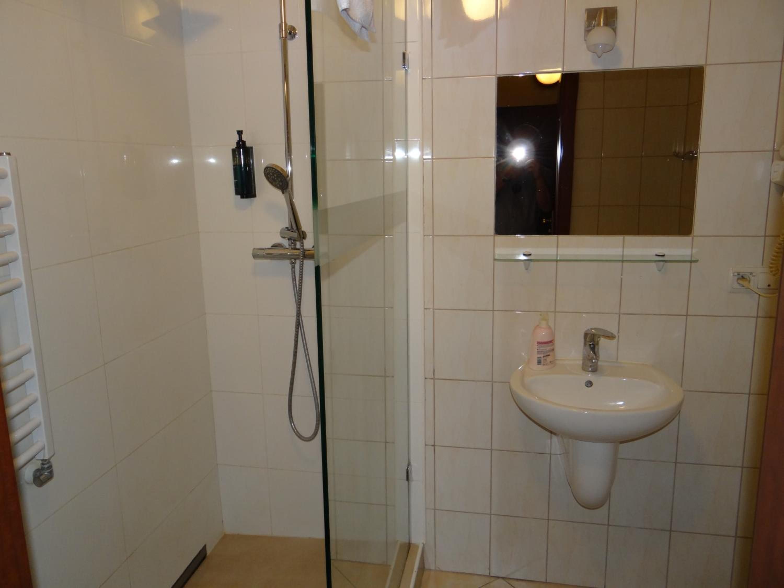 A bathroom with a glass-enclosed shower, a white sink, and a mirror above it.