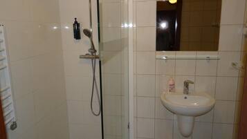 A bathroom with a glass-enclosed shower, a white sink, and a mirror above it.