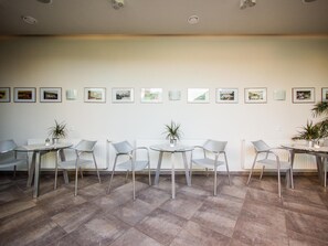 A room with a long table and chairs, a radiator, and framed pictures on the wall. - Hotel Krystal (Luhačovice)