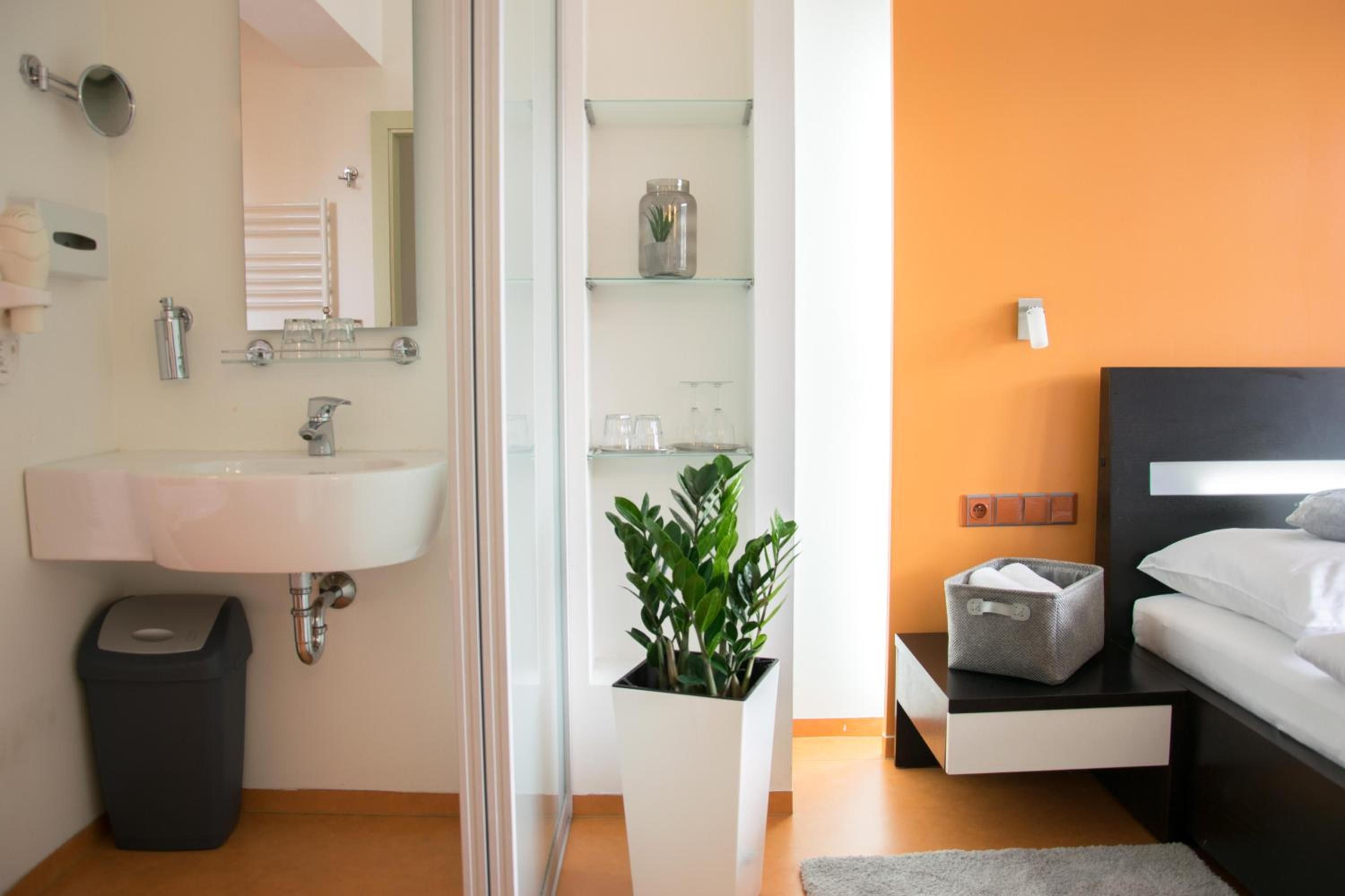 A modern bathroom with a large sink, mirror, and glass shelving unit.