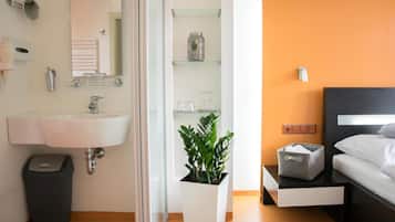 A modern bathroom with a large sink, mirror, and glass shelving unit.