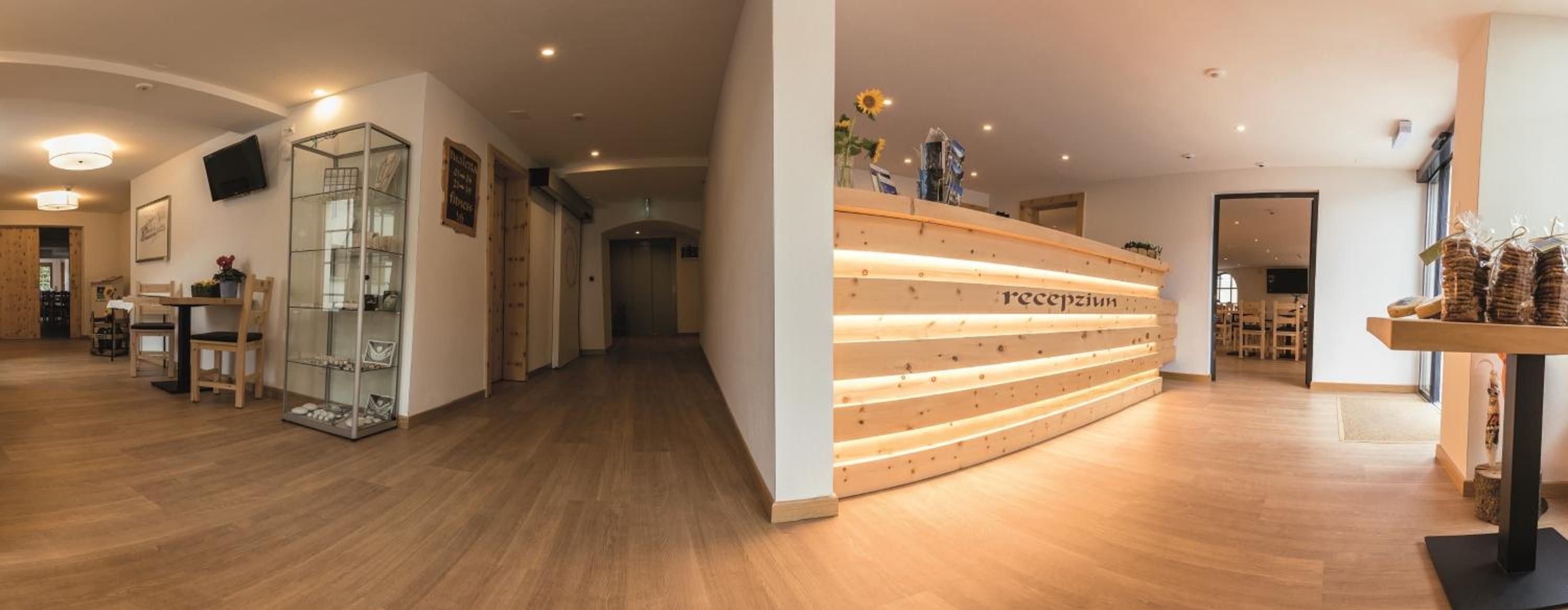 Un área de recepción con un mostrador de madera, una vitrina de vidrio y un pasillo que conduce a otras habitaciones.
