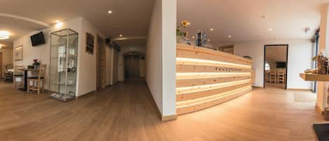 Un área de recepción con un mostrador de madera, una vitrina de vidrio y un pasillo que conduce a otras habitaciones.
