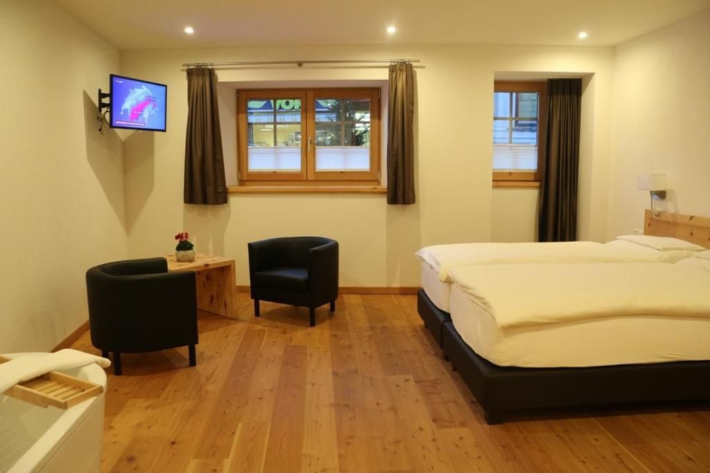 Una camera d'albergo con un letto, una scrivania, una sedia, una TV e una finestra.