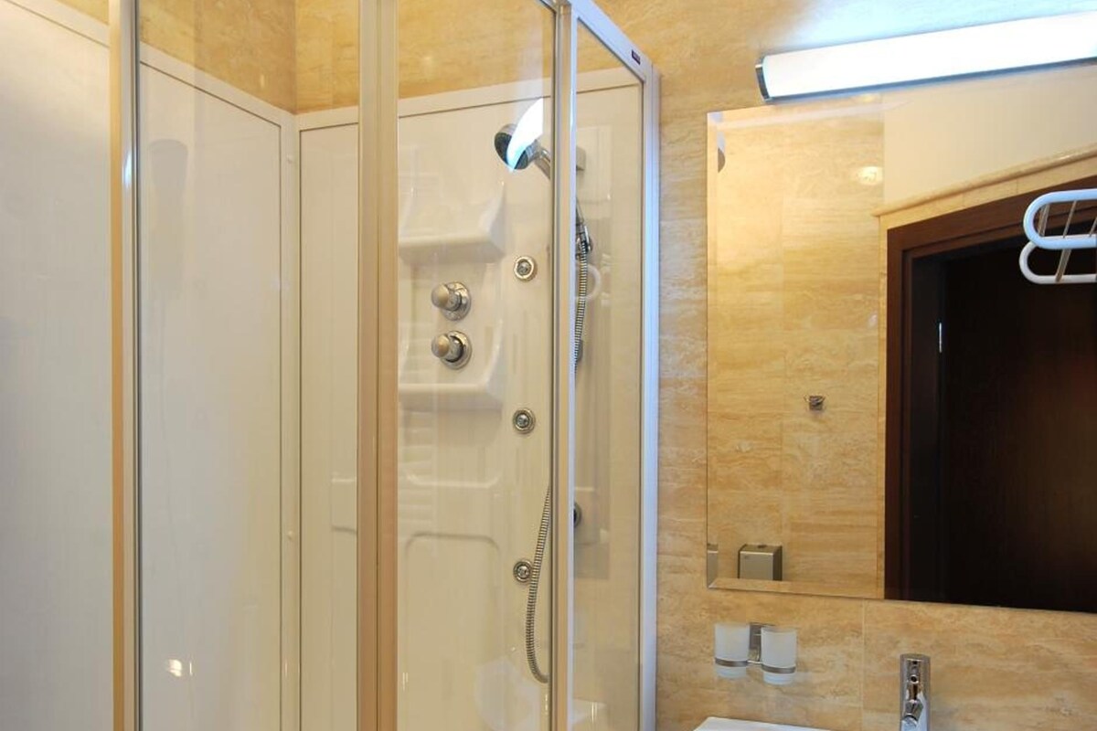 A modern bathroom with a glass-enclosed shower, a sink, and a mirror.