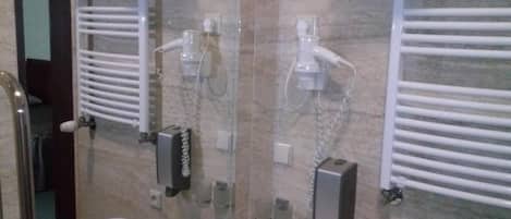 Casa de banho com lavatório, espelho, porta-toalhas e secador de cabelo.