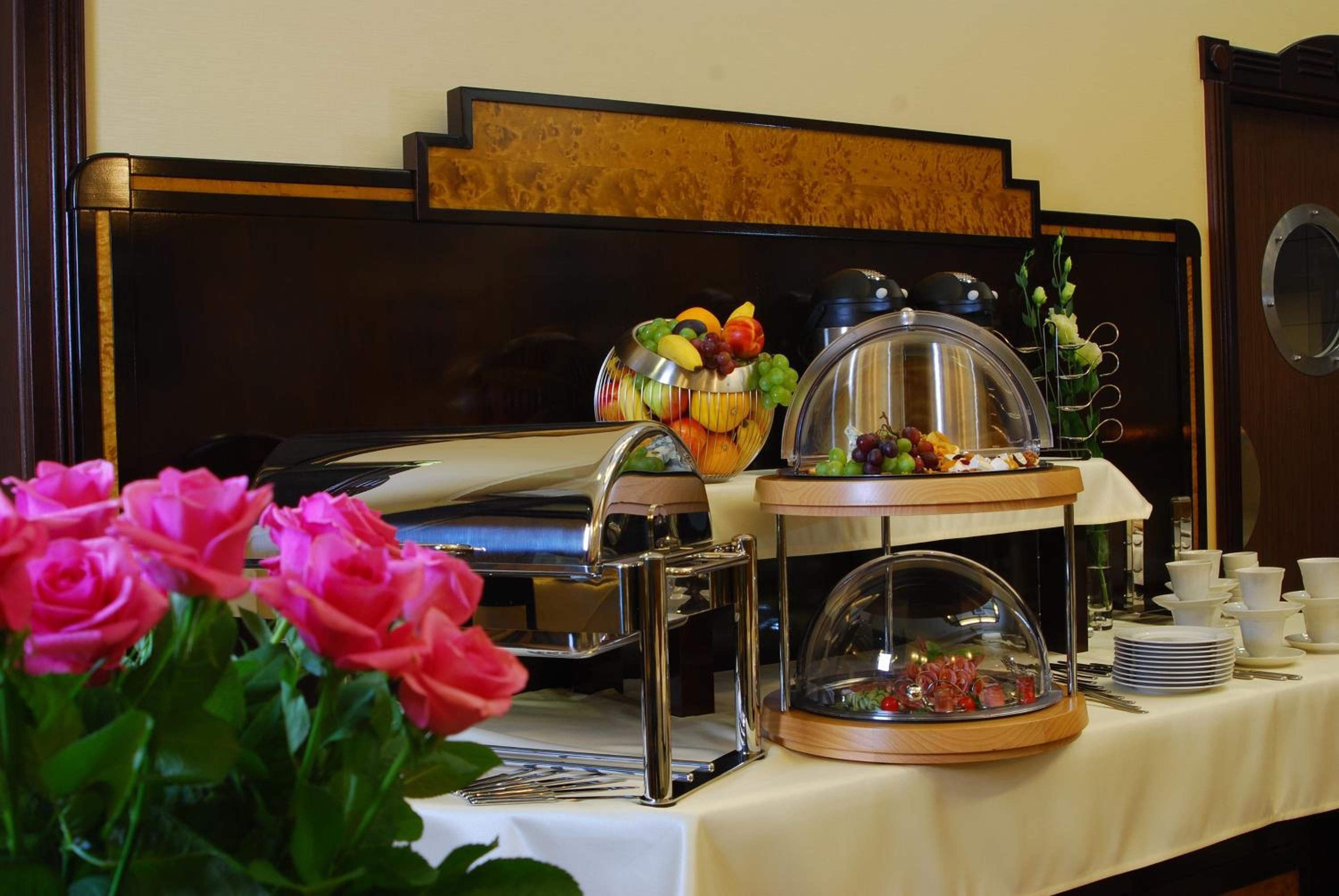 A buffet setup with a variety of food items, a coffee machine, and a floral arrangement.