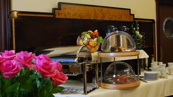 A buffet setup with a variety of food items, a coffee machine, and a floral arrangement.