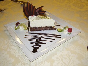 A dessert on a square plate with chocolate drizzle, garnished with lime and strawberries. - Hotel Victoria (Wloclawek)