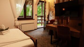 A hotel room with a bed, a desk, a chair, a television, and a view of the outdoors.