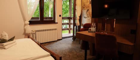 A hotel room with a bed, a desk, a chair, a television, and a view of the outdoors.