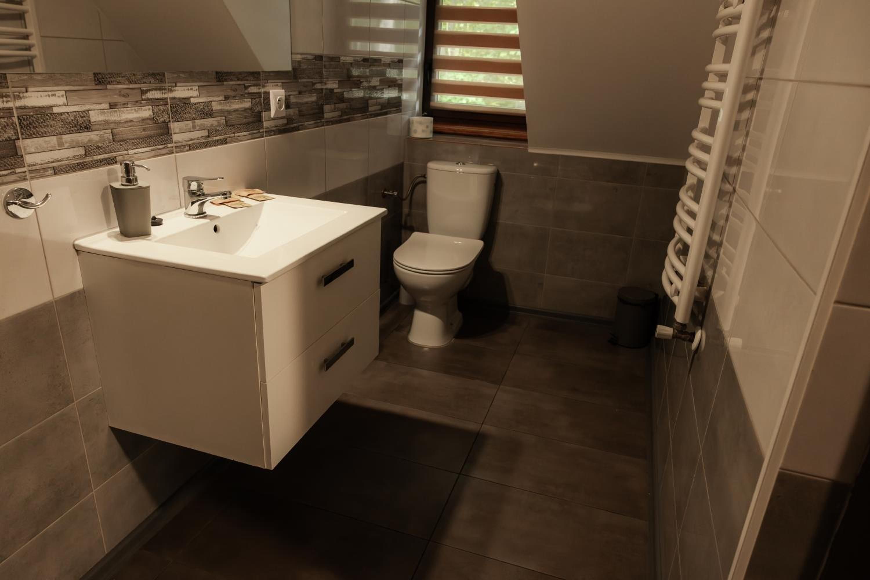 Ein Badezimmer mit einem weißen Waschbecken, einer Toilette und einer Duschkabine.