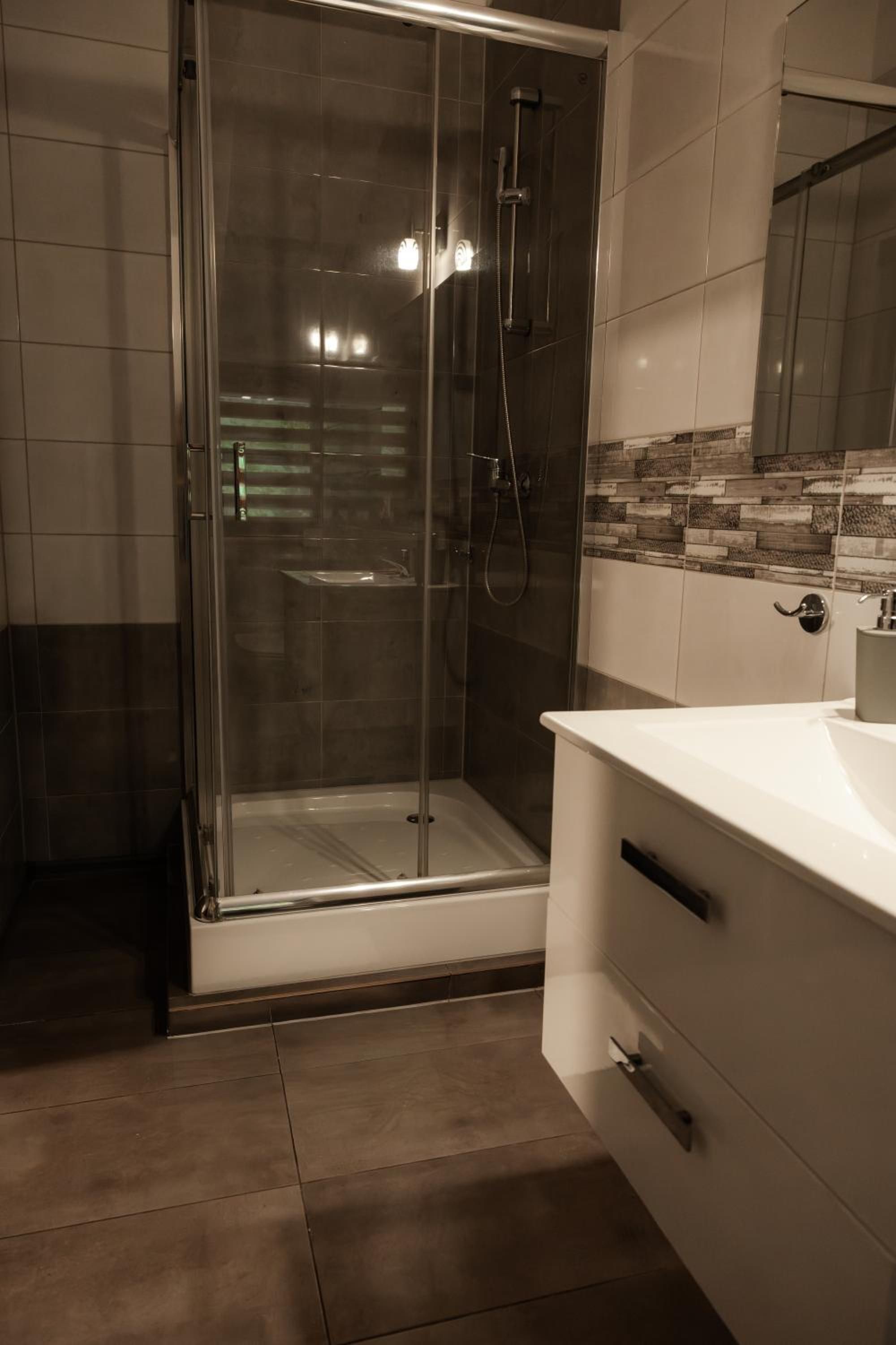 Uma casa de banho moderna com chuveiro de vidro, toucador branco e painel de azulejos.