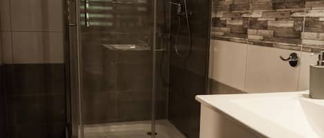 A modern bathroom with a glass-enclosed shower, a white vanity, and a tiled backsplash.