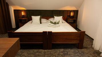 A neatly made bed with white linens, a green headboard, and two bedside tables with lamps.