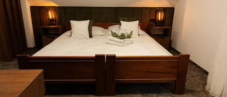 A neatly made bed with white linens, a green headboard, and two bedside tables with lamps.