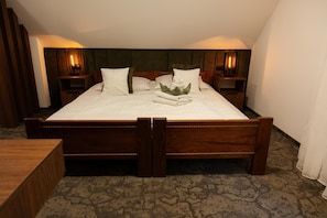 A neatly made bed with white linens, a green headboard, and two bedside tables with lamps.